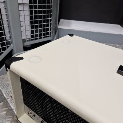 Pre-Owned EVH 5150 Iconic 80W Electric Amplifier Head A close-up of a cream-colored guitar amplifier or speaker cabinet corner, showing black corner protectors and a black front grille, set against a dark background.