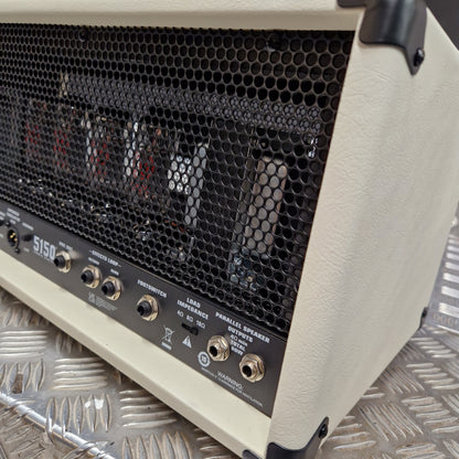 Pre-Owned EVH 5150 Iconic 80W Electric Amplifier Head Close-up of the rear corner of a cream-colored Marshall 5150 guitar amplifier head, showing the black honeycomb grille, control knobs, and internal components behind the grille, resting on a diamond plate metal surface.