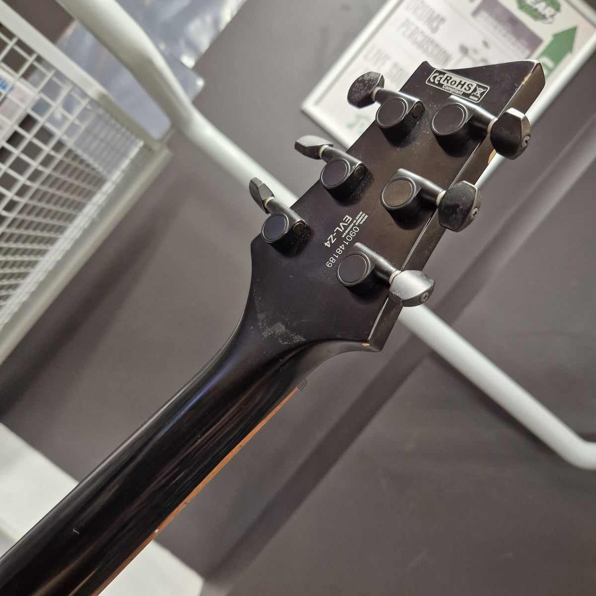 Pre-Owned Cort EVL-Z4 Electric - Satin Black Close-up of the headstock of a black Fender Stratocaster electric guitar, showing the six tuning pegs and brand logo against a blurred indoor background.