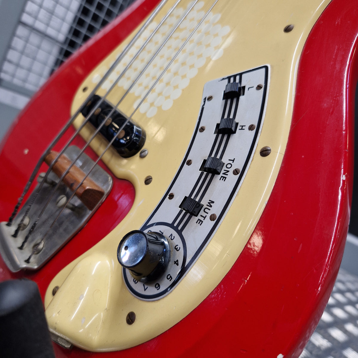 Pre-Owned Hagstrom Futurama Deluxe 1960s Bass - Red Close-up of a red and cream electric bass guitar body showing the tone and mute control panel, with part of the neck and strings visible.