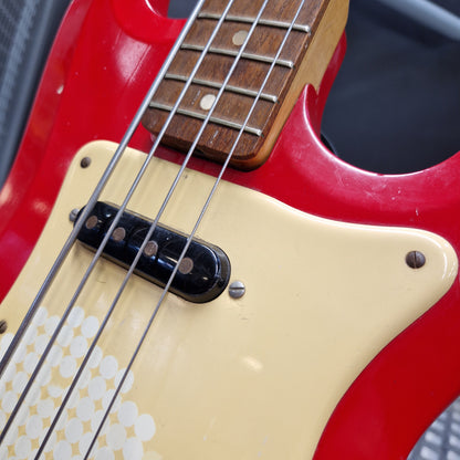 Pre-Owned Hagstrom Futurama Deluxe 1960s Bass - Red Close-up of a red electric bass guitar body with a cream pickguard, black humbucker pickup, and part of the wooden fretboard.