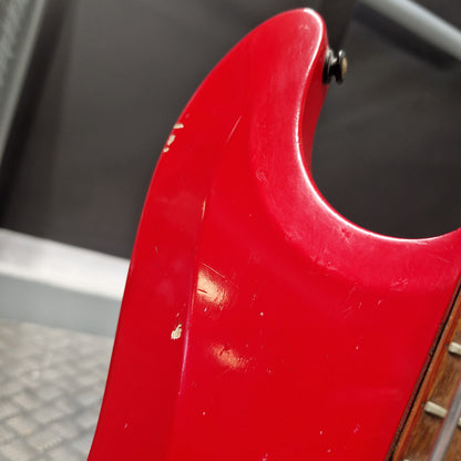 Pre-Owned Hagstrom Futurama Deluxe 1960s Bass - Red Close-up of a red electric guitar body showing the lower bout curve, a small black hardware screw, and part of a wooden fretboard.