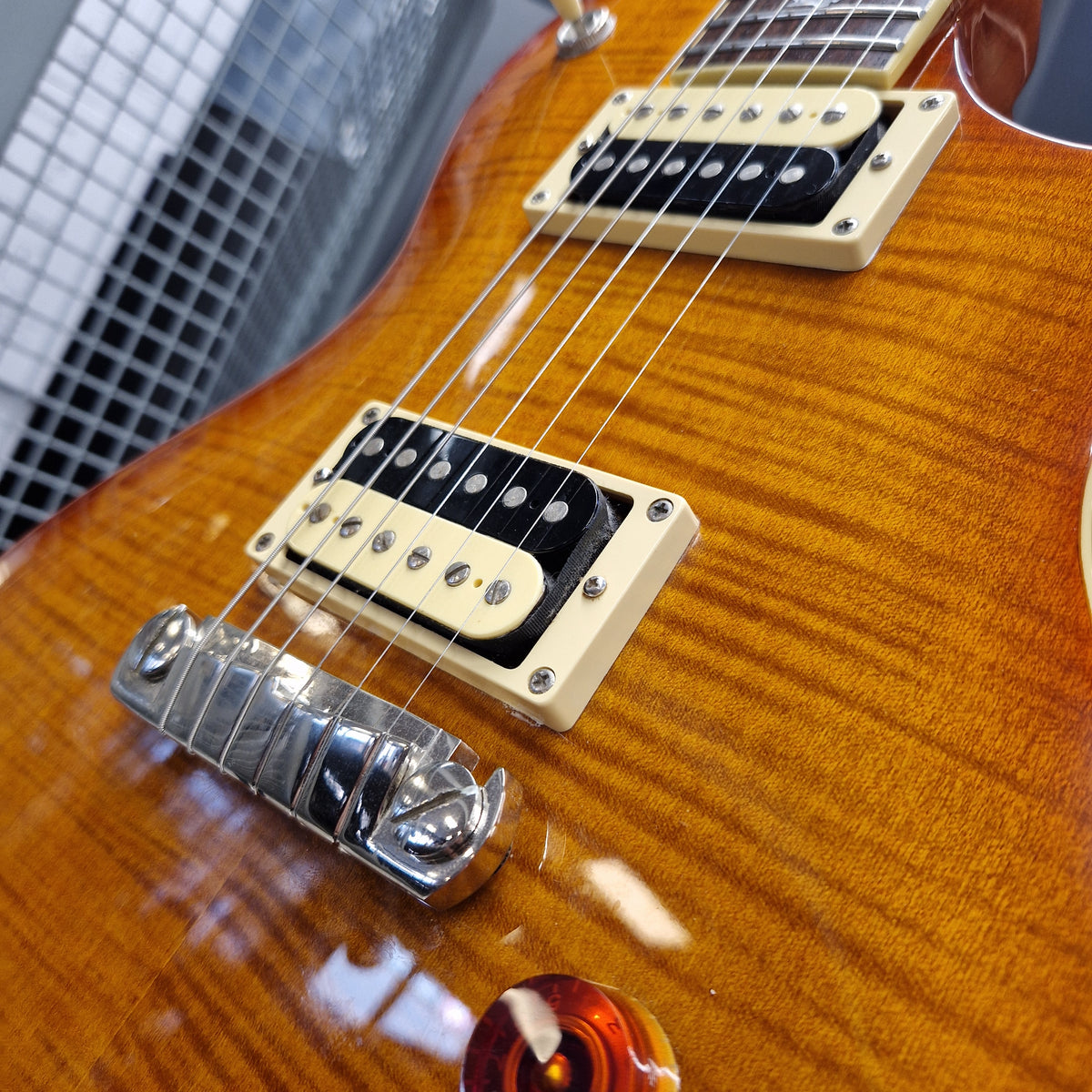 Pre-Owned PRS SE Bernie Marsden Signature Electric - Vintage Sunburst Close-up of a guitar body showing two humbucker pickups, a chrome bridge, and a glossy flamed maple wood finish.