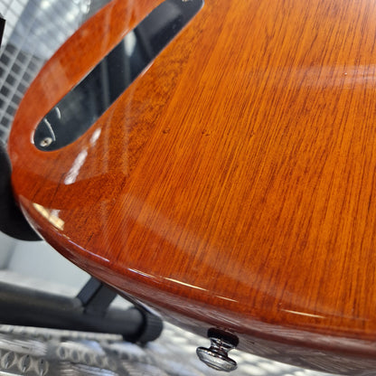Pre-Owned PRS SE Bernie Marsden Signature Electric - Vintage Sunburst Close-up of a glossy reddish-brown wooden guitar body with visible wood grain, a cutout opening, and a small metal knob, photographed indoors against a gray mesh-like background.