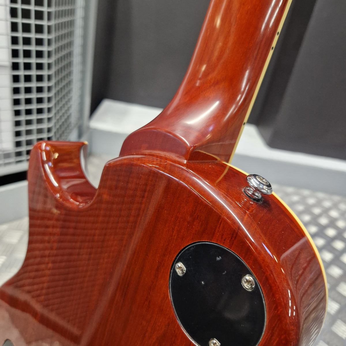 Pre-Owned PRS SE Bernie Marsden Signature Electric - Vintage Sunburst Close-up of the glossy reddish-brown body of an electric guitar, showing part of the neck, a black circular control area, and metal hardware against a gray background.