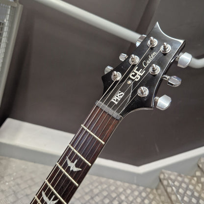 Pre-Owned PRS SE Custom 22 Semi-Hollow Electric Korean - Grey Black Close-up of the headstock and upper fretboard of a guitar, showing the brand name 'GS' and model 'Caddix' on a black headstock with silver tuning pegs.