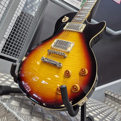 Pre-Owned Epiphone Les Paul Standard Pro Electric - Vintage Sunburst A close-up of a sunburst electric guitar body on a stand, showing a glossy yellow-to-brown-to-black flame finish with gold hardware and a black pickguard.