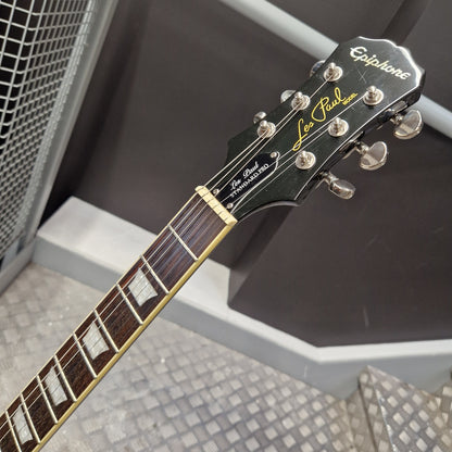 Pre-Owned Epiphone Les Paul Standard Pro Electric - Vintage Sunburst Close-up of an Epiphone Les Paul Custom electric guitar headstock and fretboard, showing the black wood headstock with gold lettering and silver tuning pegs, and the dark fretboard with gold block inlays.