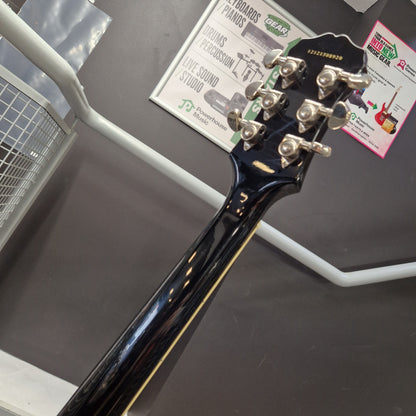 Pre-Owned Epiphone Les Paul Standard Pro Electric - Vintage Sunburst Close-up of the headstock of a glossy black electric guitar, showing six silver tuning pegs and part of the neck, photographed indoors against a dark gray surface with white display brackets.