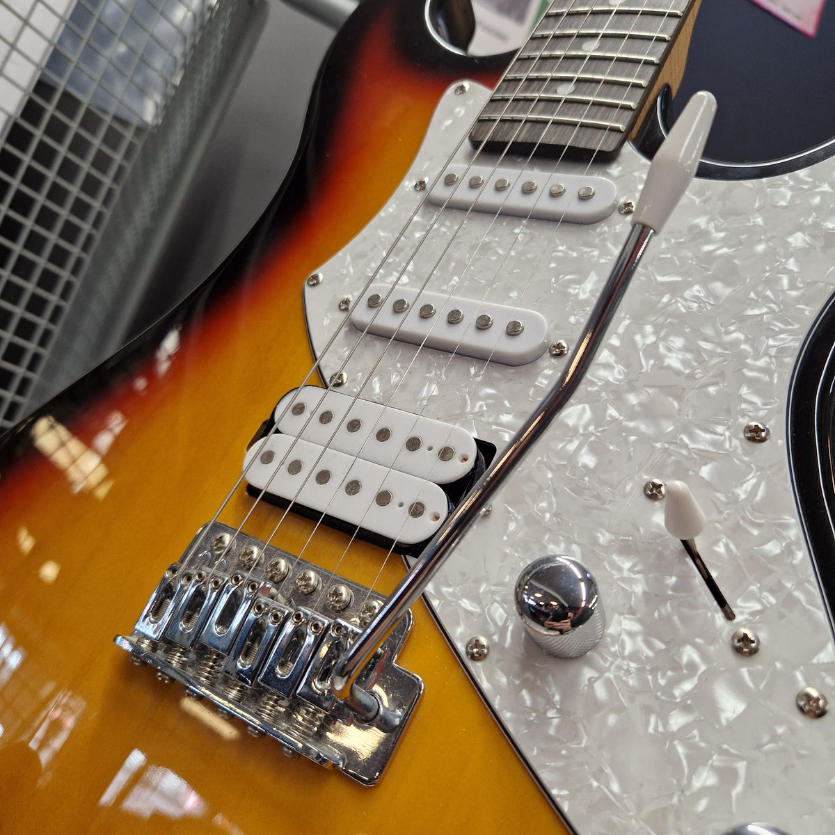 Pre-Owned Aria Pro II 714 Series Electric - Sunburst Close-up of an electric guitar body showing a sunburst finish, white pearl pickguard, dual humbucker pickups, and a chrome bridge with a white string retainer.