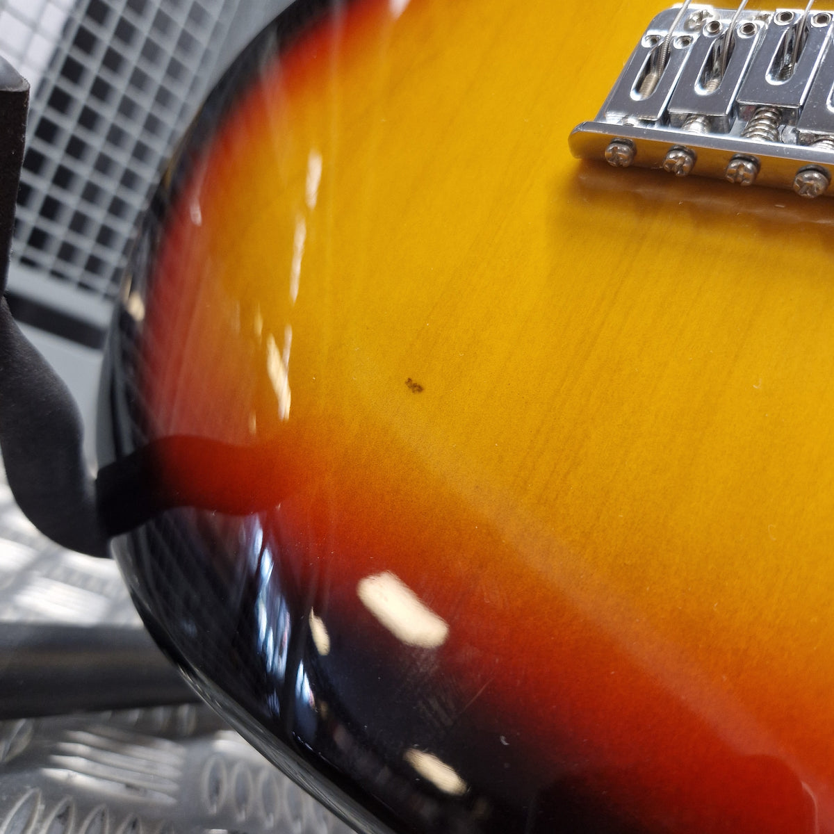 Pre-Owned Aria Pro II 714 Series Electric - Sunburst Close-up of a sunburst electric guitar body showing the yellow-to-brown-to-black gradient finish and part of the chrome bridge.