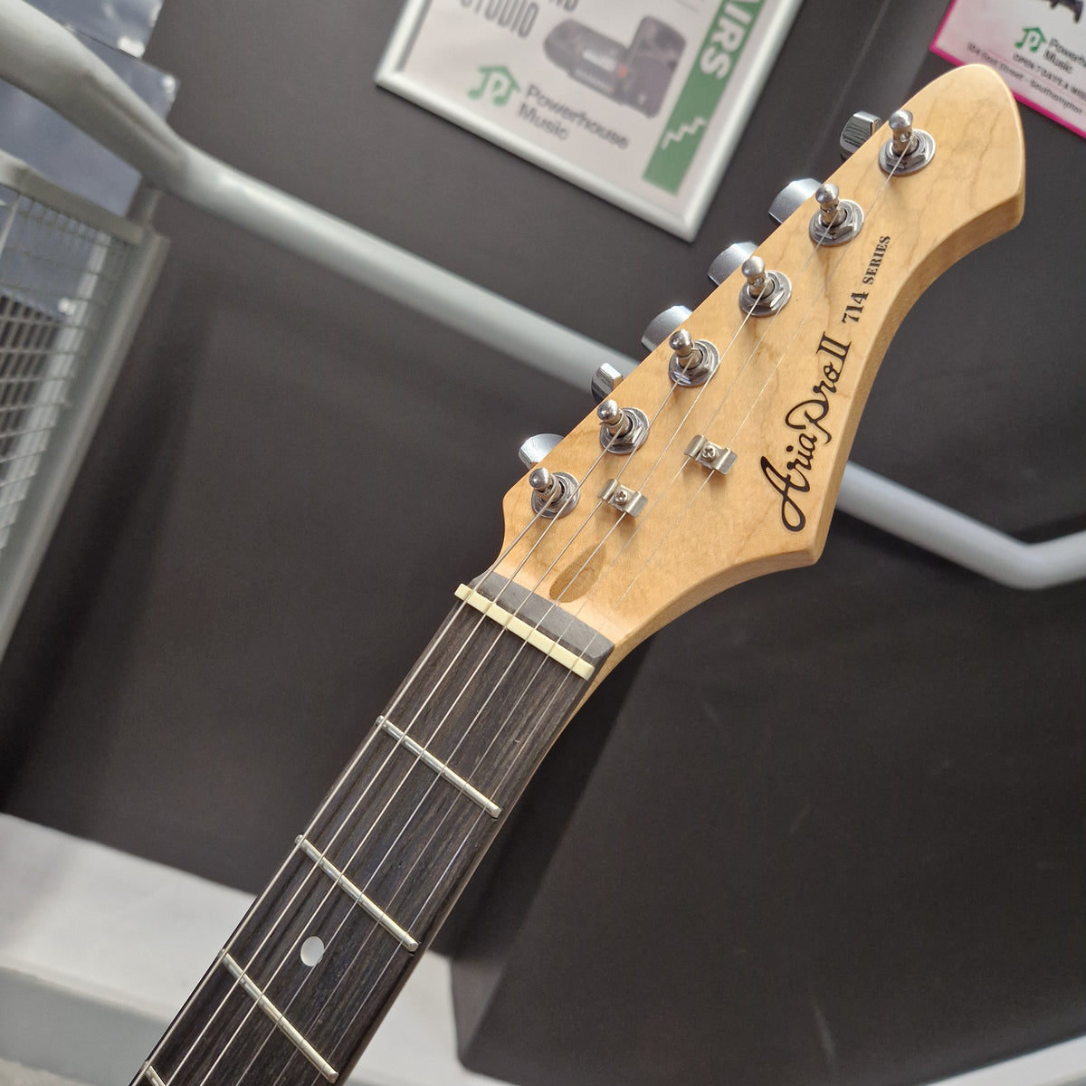 Pre-Owned Aria Pro II 714 Series Electric - Sunburst Close-up of a guitar headstock and upper fretboard, showing the brand name 'Guiseppe' and model '714 Master'. The headstock has a natural light wood finish with silver tuning pegs, set against a dark gray background.