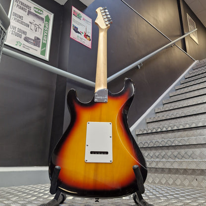 Pre-Owned Aria Pro II 714 Series Electric - Sunburst A sunburst electric guitar shown from the back, hanging on a display stand in a store or showroom. The guitar features a classic orange-to-black gradient finish, a white pickguard, and a light wood neck.