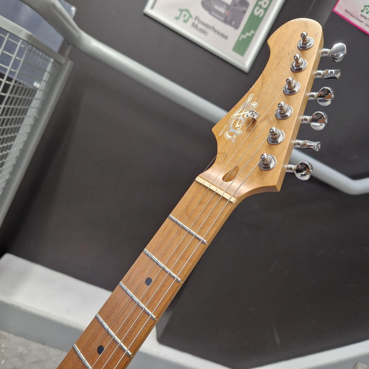 Pre-Owned Jet JS-300 Left-Handed Electric - Sunburst Close-up of a guitar headstock and upper fretboard, showing a natural wood finish, six silver tuning pegs, and inlays on a dark display background.