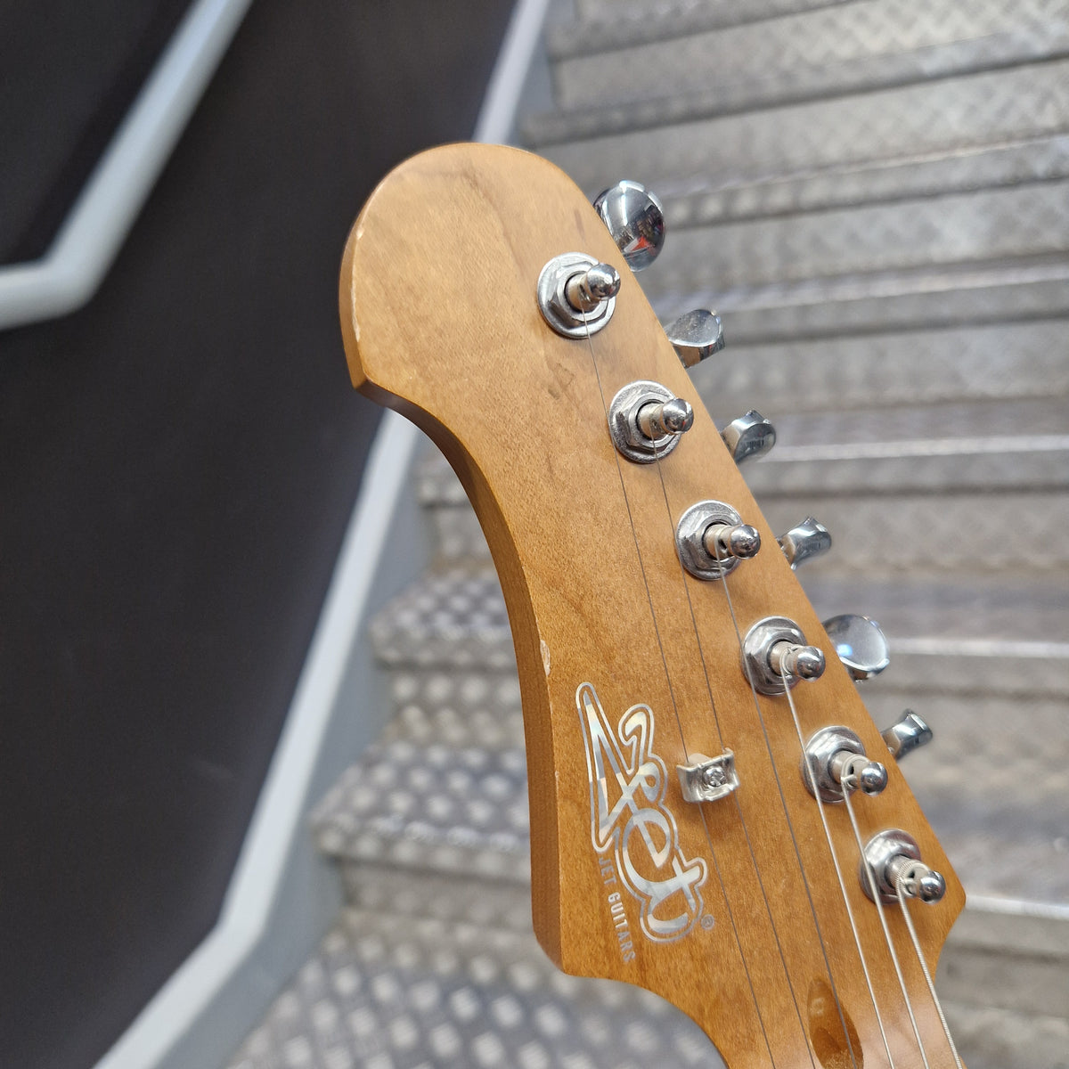 Pre-Owned Jet JS-300 Left-Handed Electric - Sunburst Close-up of an electric guitar headstock with a natural wood finish, chrome tuning pegs, and a stylized logo printed on the back.