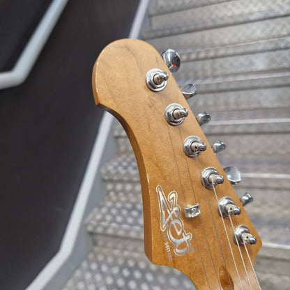 Pre-Owned Jet JS-300 Left-Handed Electric - Sunburst Close-up of an electric guitar headstock with a natural wood finish, chrome tuning pegs, and a stylized logo printed on the back.