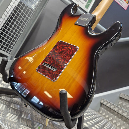 Pre-Owned Jet JS-300 Left-Handed Electric - Sunburst Close-up of the back of a glossy sunburst electric guitar resting on a stand in a store or workshop setting.