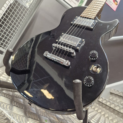 Pre-Owned Marshall MGAP Singlecut Electric - Black Gloss A glossy black electric guitar body with chrome hardware and a visible 'Gibson' logo badge, photographed indoors on a display stand.