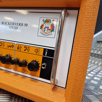 Pre-Owned Orange Rockerverb 50H MKIII Valve Electric Amplifier Head Close-up of an orange textured guitar amplifier cabinet with a white control panel, black knobs, a chrome pull handle, and a small Rockerverb 50 NK III logo.