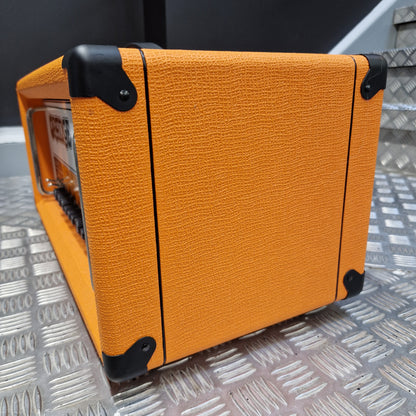 Pre-Owned Orange Rockerverb 50H MKIII Valve Electric Amplifier Head An orange textured guitar amplifier cabinet with black corner protectors, photographed on a silver diamond plate metal surface.