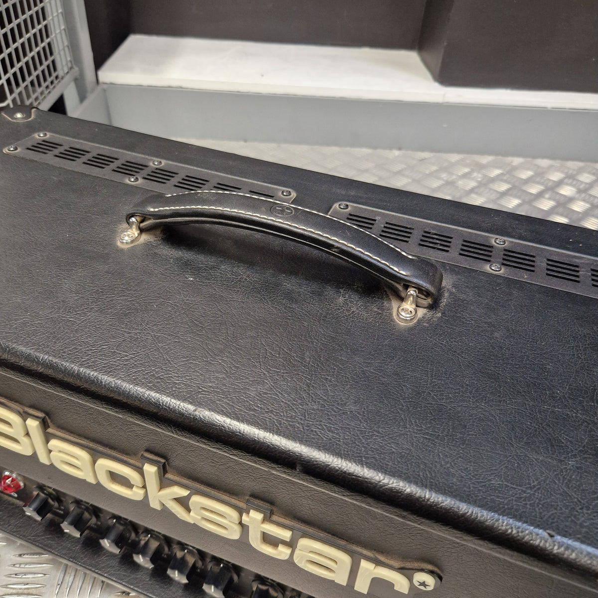 Pre-Owned Blackstar HT Club 50 Electric All-Valve Amplifier Head Close-up of a black amplifier cabinet with a metal handle and part of the 'blackstar' logo on the side, photographed indoors.