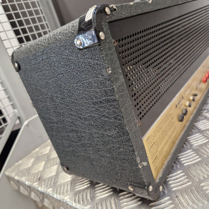 Pre-Owned Marshall JCM2000 DSL100 Valve Electric Amplifier Head A close-up of a black textured speaker cabinet corner with metal lugs and a perforated metal top grille, photographed against a diamond-plate metal background.