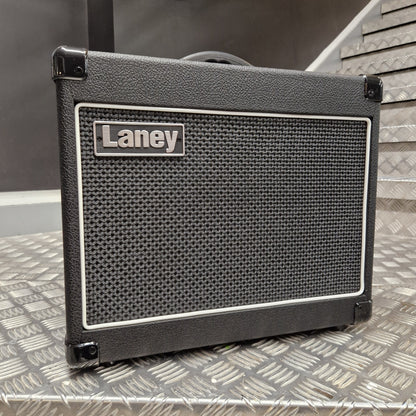 Pre-Owned Laney LG20R 20w Electric Guitar Combo A black Laney speaker cabinet with a textured front grille and a silver brand badge, photographed on a diamond plate metal surface.