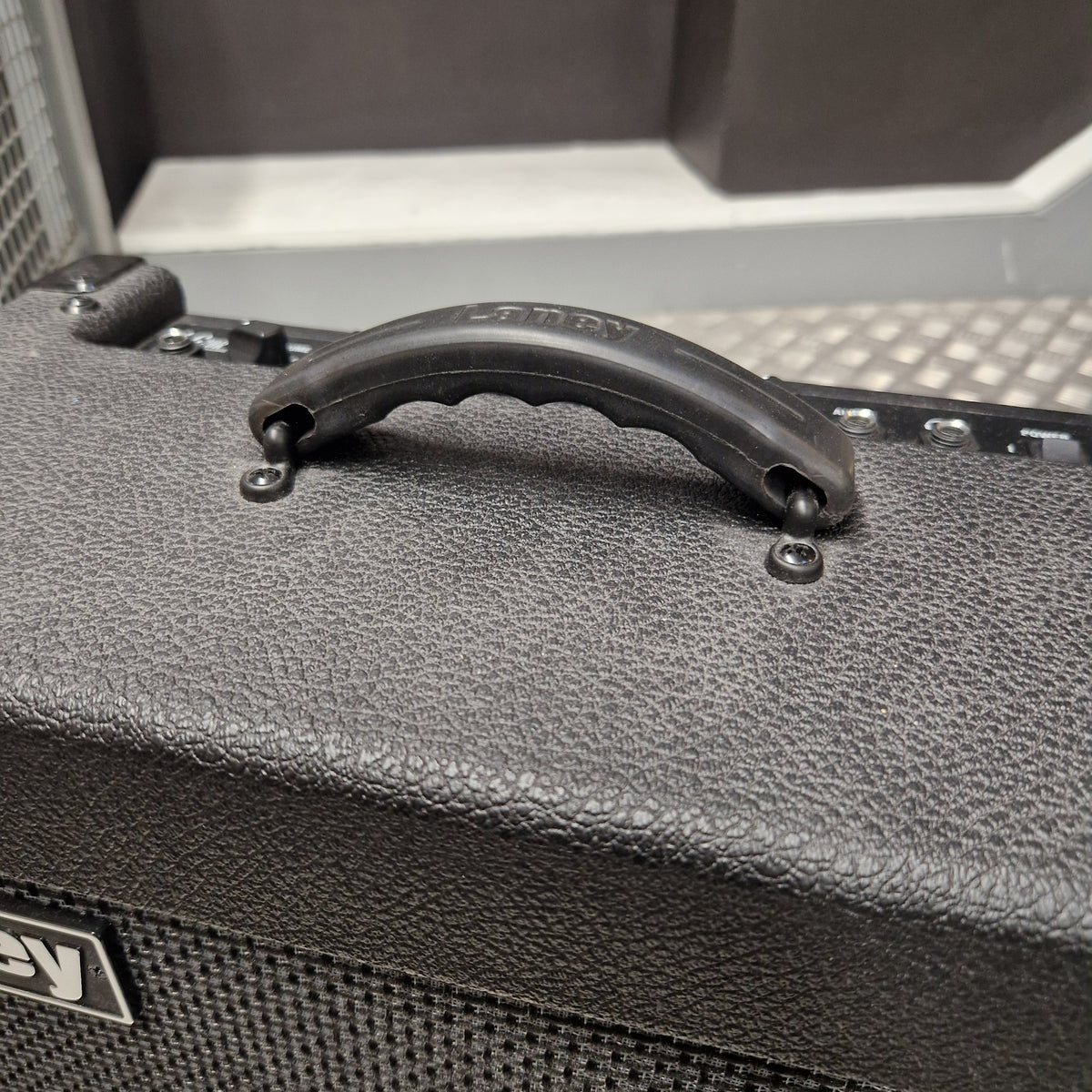 Pre-Owned Laney LG20R 20w Electric Guitar Combo Close-up of a black textured guitar amplifier cabinet handle with mounting screws, showing the side grille and a small logo badge.