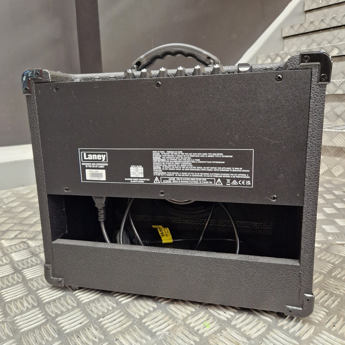 Pre-Owned Laney LG20R 20w Electric Guitar Combo A black L-Acoustic HP8000 speaker cabinet shown from the back, with the rear panel, handle, and internal wiring visible, placed on a diamond-plate metal surface.