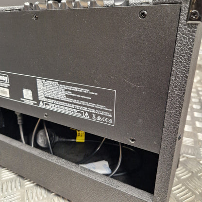Pre-Owned Laney LG20R 20w Electric Guitar Combo Close-up of the underside of a black equipment case or speaker cabinet, showing screws, a product info label, and internal wiring in a metallic diamond-plate floor setting.