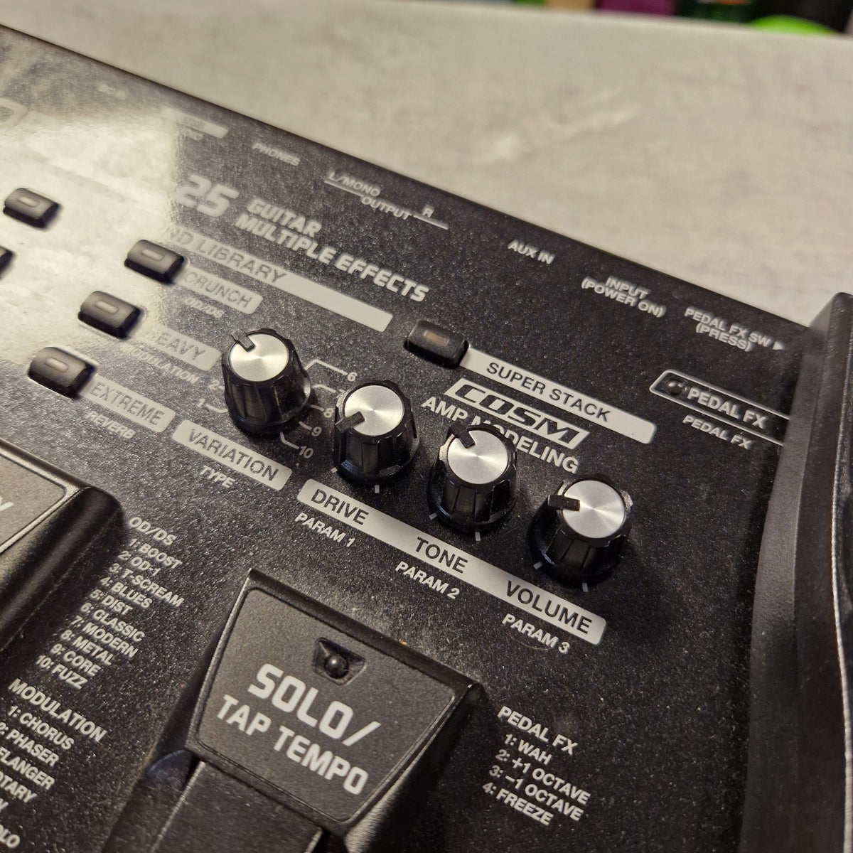 Pre-Owned Boss ME-25 Multi-Effects Pedal Close-up of a black Fender Solo/Tap Tempo multi-effects guitar pedal control panel with silver and black knobs, including Superstak, Amp Modeling, Volume, Tone, Drive, and FX Send.