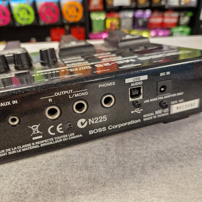 Pre-Owned Boss ME-25 Multi-Effects Pedal Close-up of the rear panel of a Boss N225 audio device, showing input and output jacks, knobs, and branding on a gray surface.