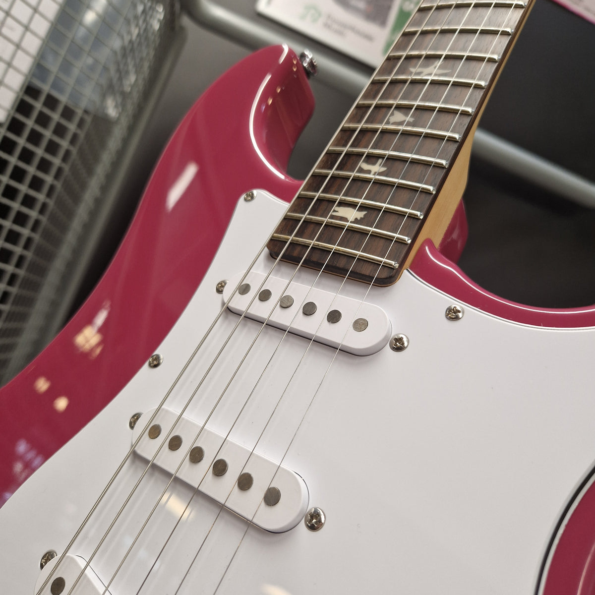 Pre-Owned PRS SE Silver Sky John Mayer Signature Electric - Dragonfruit w/ Gig Bag - Close-up of an electric guitar body showing a glossy white pickguard and body contour with a vibrant pink/magenta lower bout and upper bout trim, alongside a dark fretboard and silver hardware.
