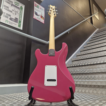 Pre-Owned PRS SE Silver Sky John Mayer Signature Electric - Dragonfruit w/ Gig Bag - A pink electric guitar shown from the back, resting on a display stand in a store or showroom with metal panel walls and informational signs visible in the background.
