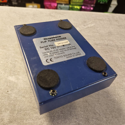 Pre-Owned Guyatone Flip TD-X Tube Echo Hybrid Tube Power Delay Pedal - A blue Equitone flip tube power amplifier control box with four black rubber feet and a white label, photographed on a gray textured surface.