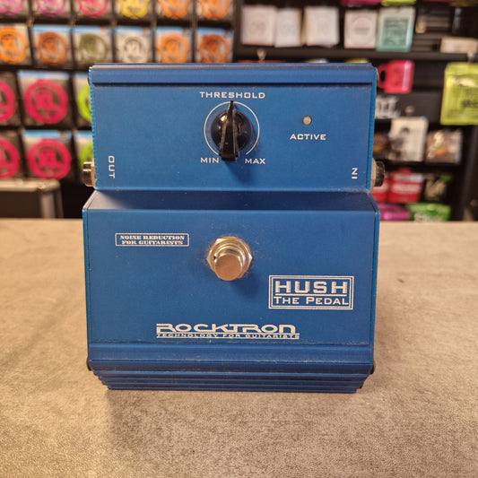 Pre-Owned Rocktron Hush Noisegate Pedal - A blue Rocktron Hush The Pedal guitar effects unit with a footswitch, set on a gray surface with a blurred store background.