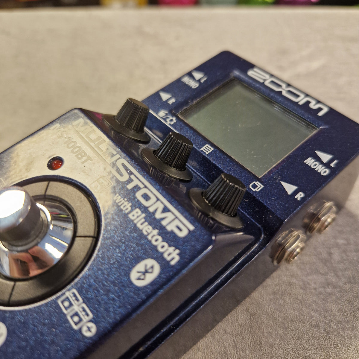 Pre-Owned Zoom MS-100BT MultiStomp Guitar Pedal with Bluetooth - A close-up of a blue Moenstomp with Bluetooth guitar effects pedal, showing its front controls, knobs, and display screen.