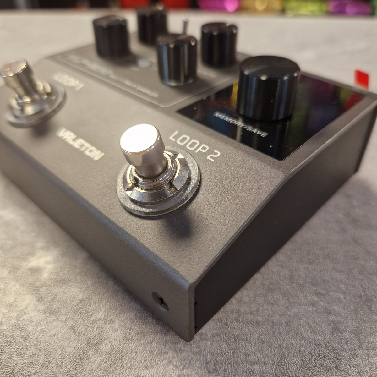 Pre-Owned Valeton VLP-200 Multi-Track Sampler w/ Box - A close-up shot of a Voxeteration Vileton guitar effects pedal, featuring a matte dark gray metal body, black knobs, and silver footswitches on a textured gray surface.