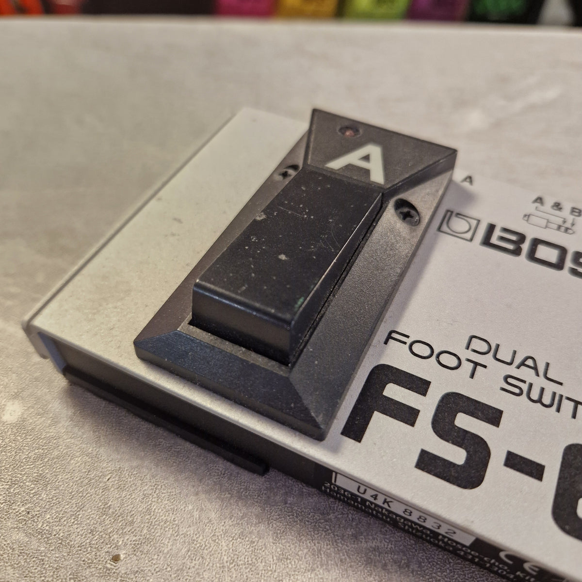 Pre-Owned Boss Dual Foot Switch FS-6 Pedal A close-up of a black dual foot switch component mounted on a silver metal base, with printed text including 'DUAL FOOT SWITCH' and partial model lettering.