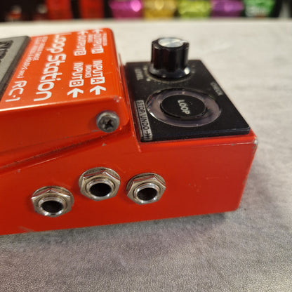 Pre-Owned Boss RC-1 Looper Pedal w/ Box - Close-up of a red Loop Station RC-1 guitar effects pedal with a black loop section, silver jacks, and white printed controls against a gray textured background.