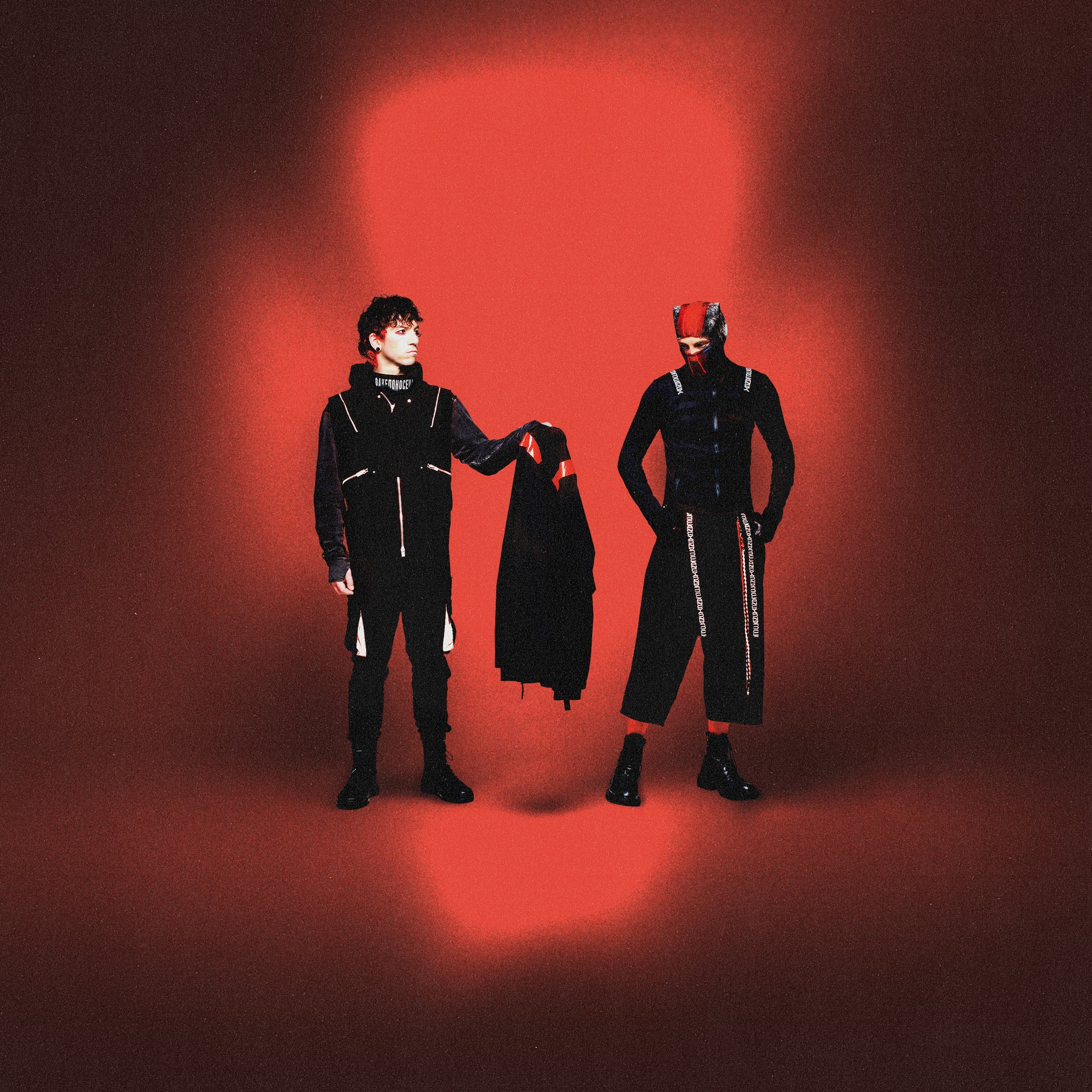 Twenty One Pilots - Breach Two people in black outfits with a red light on a dark background