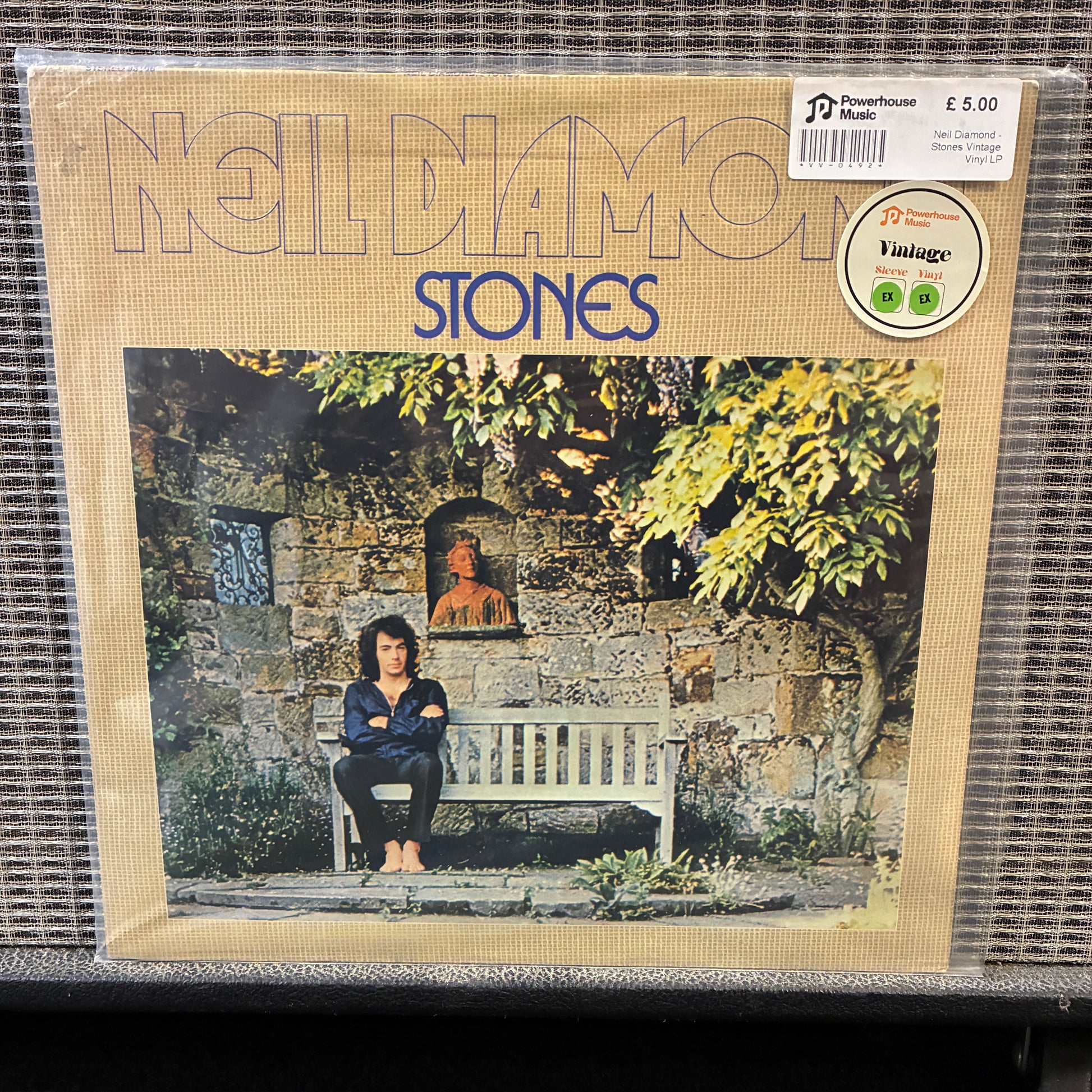 Neil Diamond - Stones Album cover of 'Noldamo Stones' with a person sitting on a bench in front of a stone wall.