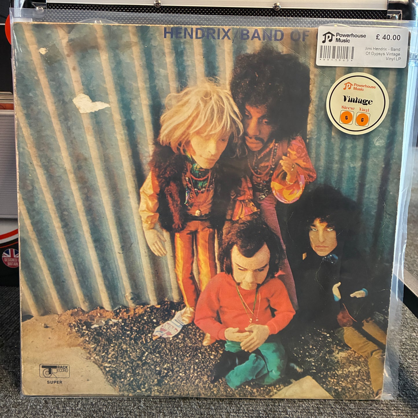 Jimi Hendrix - Band Of Gypsys Vintage Vinyl LP A vinyl record sleeve for Hendrix Band of Green Man, sealed in a clear plastic protective case. The cover art features four figures posed against a corrugated metal wall, with a 'JD Vintage Store' sticker on the top right.