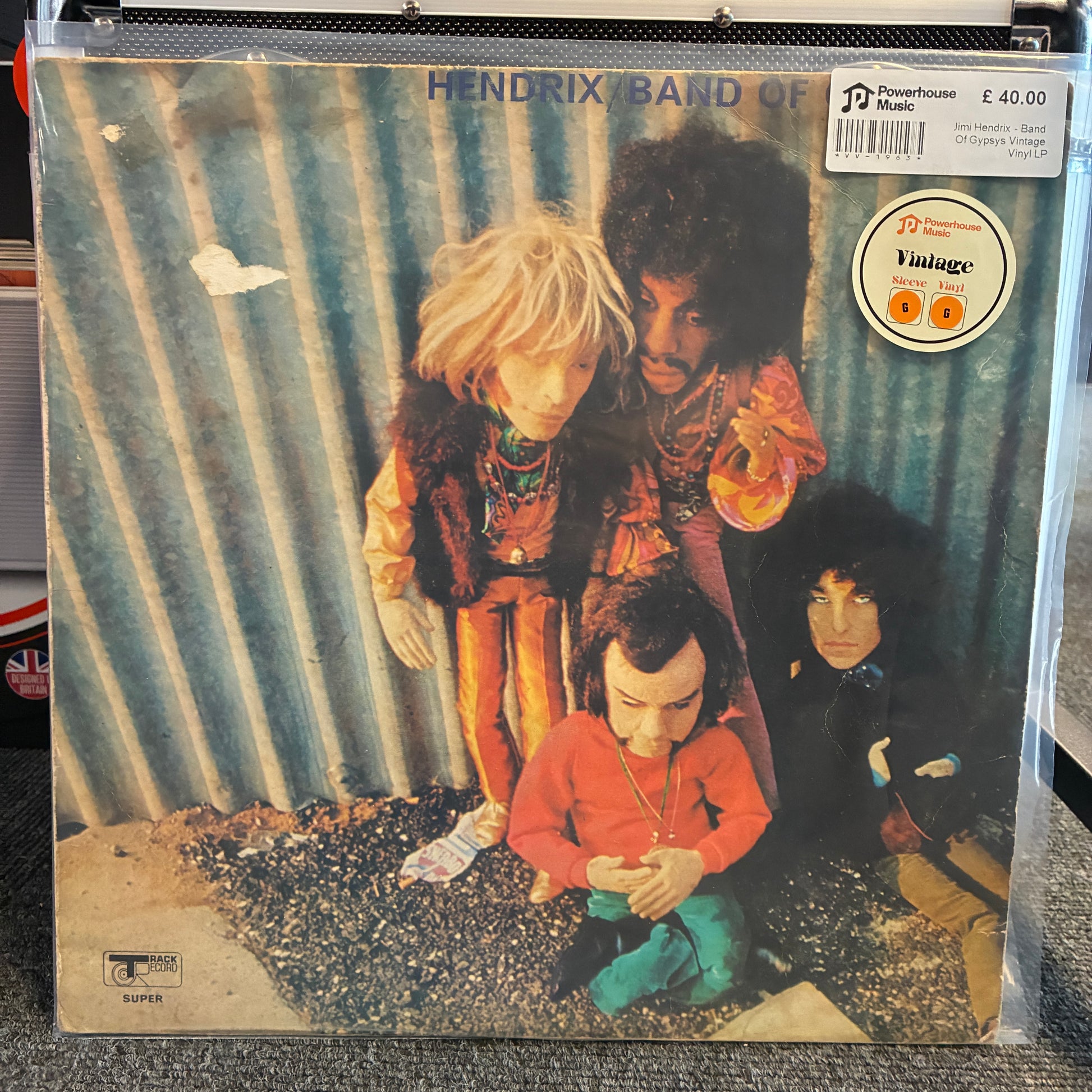 Jimi Hendrix - Band Of Gypsys Vintage Vinyl LP A vinyl record sleeve for Hendrix Band of Green Man, sealed in a clear plastic protective case. The cover art features four figures posed against a corrugated metal wall, with a 'JD Vintage Store' sticker on the top right.