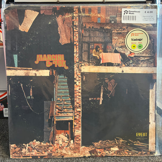 Mancini & Fox - Mancini & Fox Vintage Vinyl LP A vintage vinyl record sleeve for Marcion & Tom's 'Event' album, sealed in a protective plastic sleeve. The cover art features a dark, gritty collage of brick buildings, a staircase, and debris, with the band's name in orange text.
