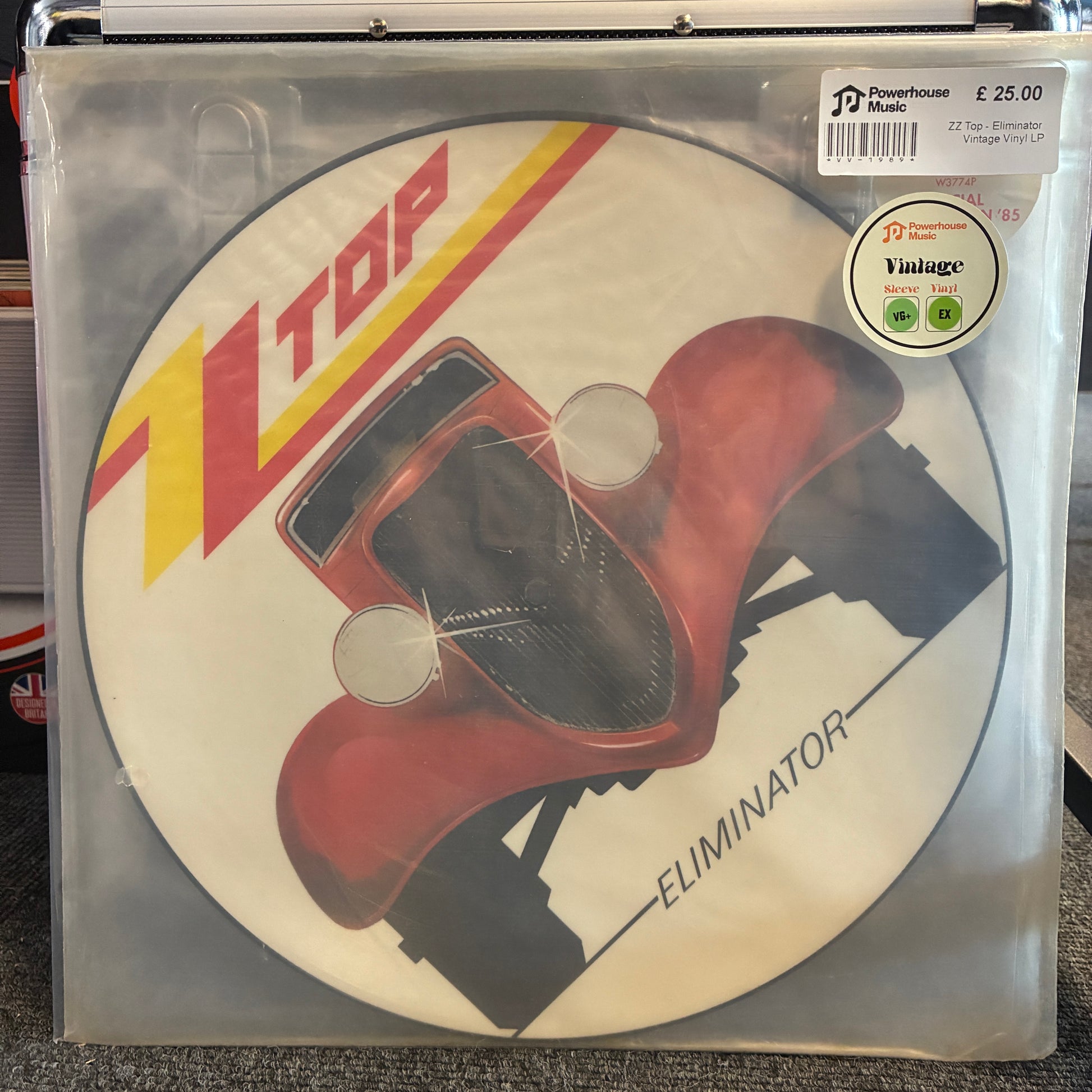 ZZ Top - Eliminator (Picture Disc) Vintage Vinyl LP A vinyl record sleeve for X-Top's 'Eliminator' LP, showing a red race car illustration on a white circular background. The sleeve is inside a clear plastic protective case, with a price sticker and a Vintage Records sticker visible on the top right.