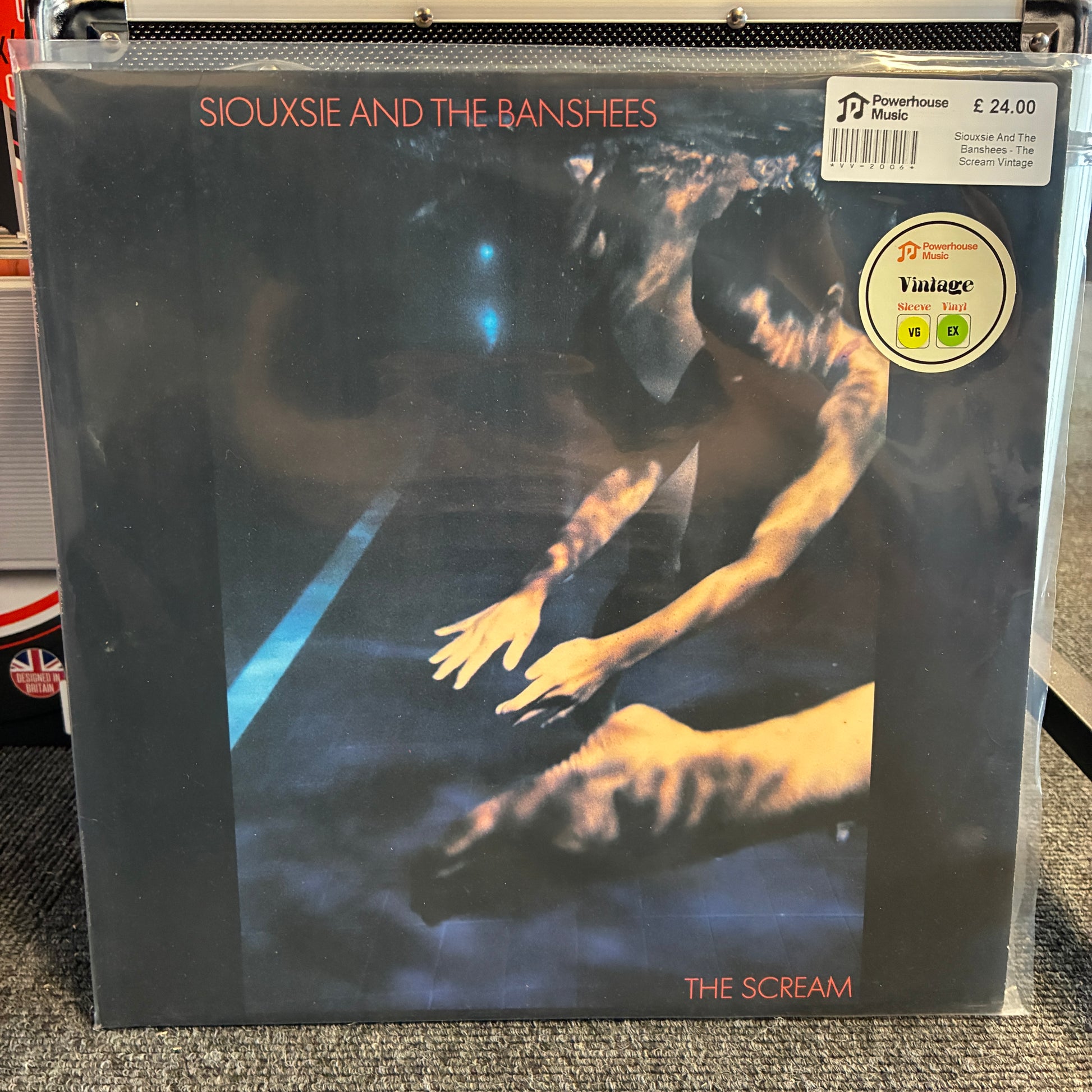 Siouxsie And The Banshees - The Scream Vintage Vinyl LP Siouxsie and the Banshees - The Scream vinyl record album in a clear protective plastic sleeve, photographed on a carpeted floor. The cover art features a dark, moody scene with a figure reaching out, and a prominent circular 'Vintage' sticker is visible in the top right corner.