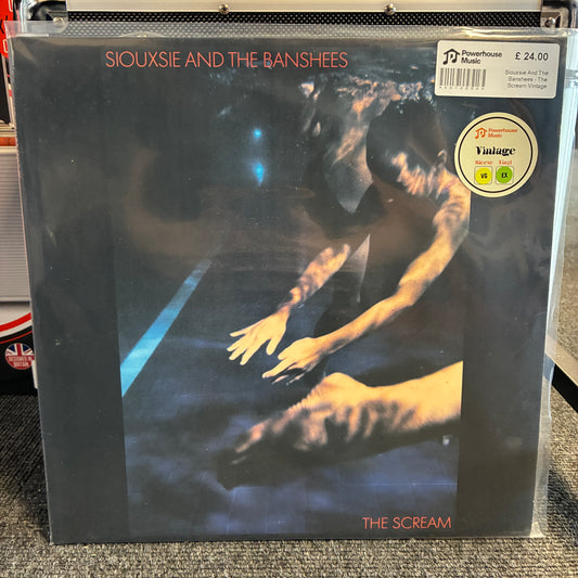Siouxsie And The Banshees - The Scream Vintage Vinyl LP Siouxsie and the Banshees - The Scream vinyl record album in a clear protective plastic sleeve, photographed on a carpeted floor. The cover art features a dark, moody scene with a figure reaching out, and a prominent circular 'Vintage' sticker is visible in the top right corner.