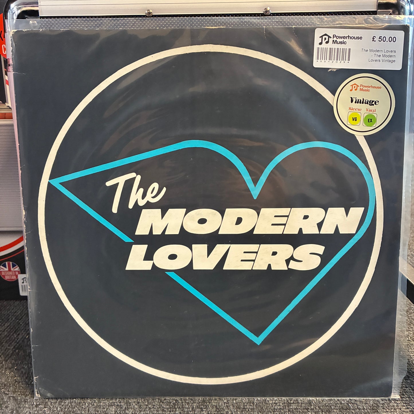 The Modern Lovers - The Modern Lovers Vintage Vinyl LP The Modern Lovers vinyl record sleeve on a record store shelf, featuring a black background with a cream circle, a light blue heart outline, and cream text.