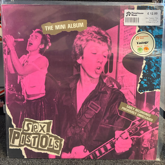 Sex Pistols -The Mini Album  Vintage Vinyl LP Sex Pistols 'The Mini Album' vinyl record cover, featuring a pink and black photo of the band members with torn-paper style text overlays. A white barcode sticker and a circular 'Vintage' label are visible on the top right.